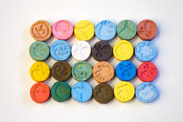 Fototapeta na wymiar Several pills of MDMA (Extasy) on white table distributed by drug dealer