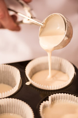 cropped shot of confectioner pouring dough into baking forms