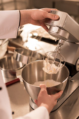 partial view of confectioner making cream for dessert in restaurant kitchen