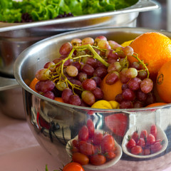 Fresh fruit grapes, orange in a silver bowl. Fresh greens, lettuce in the background