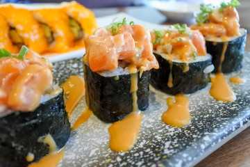Sushi Roll, Japanese style cooking. Sushi Rice filled with various ingredients and topping with salmon spicy sauce.