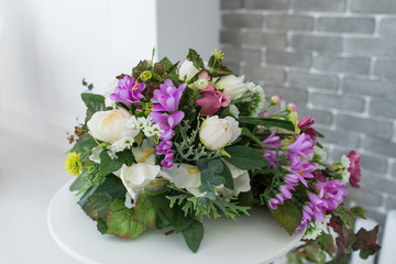 Bouquet of white and purple flowers on the white little table. 