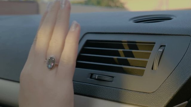 Hand of woman turning ac heat on in car 