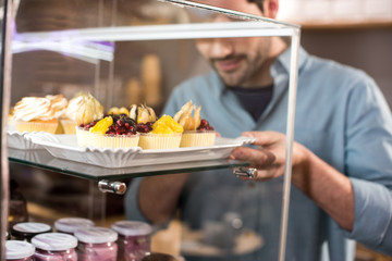 selective focus of barista taking pastry out box in coffee shop