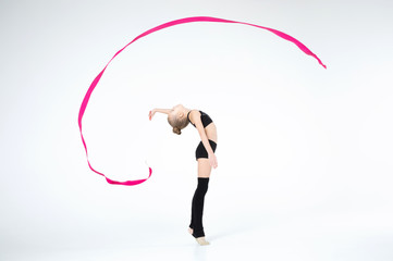Rhythmic gymnastics caucasian blonde girl in black suite performing athelete exercises with pink...