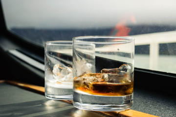 Two glasses of whiskey and Vodka with 600 years old’s ice cubes of the Grey Glacier served on a ferry ride in the Grey Lake, Rainy day, Torres del Paine, Patagonia, Chile