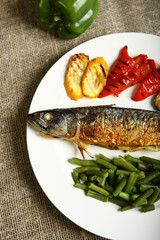 Healthy and proper food, grilled fish and vegetables with lemon and green beans on a white plate. Low-calorie food. View from above