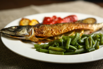 Healthy and proper food, grilled fish and vegetables with lemon and green beans on a white plate. Low-calorie food. Close-up