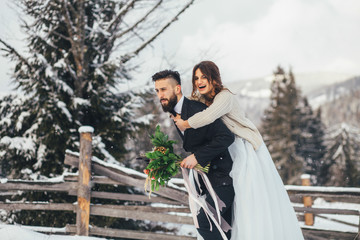 Naklejka premium Bearded man and his lovely bride pose on the snow in a magic winter forest