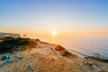 Amazing stunning unbelievable sunset at atlantic ocean in Portugal. Cape Rock fantasy seascape. View from big height at colorful scenic sea with rocks and mountains in evening. Tropical paradise.