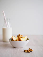 Äpfel und Nüsse in einer weißen Schale, Milchflasche