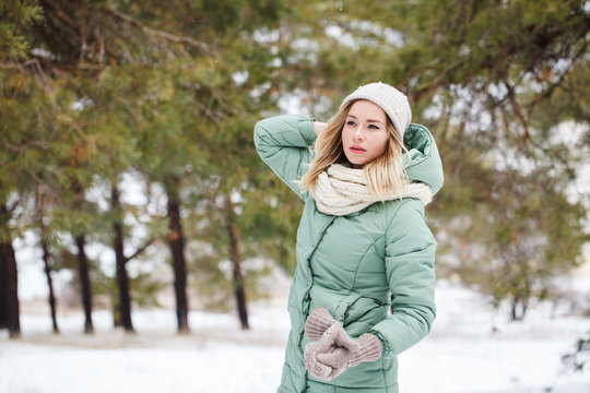 Young beautiful slender blonde girl outdoors in winter looking away. Portrait of an attractive model on a winter background. Space for text.