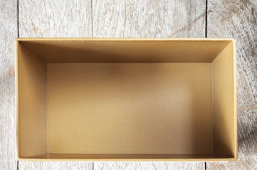 Top view of empty open cardboard box on wooden background