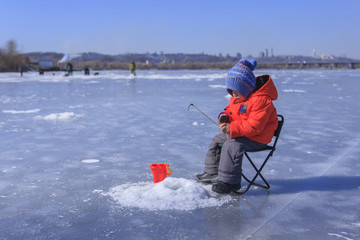 a little boy is fishing on a frozen lake
