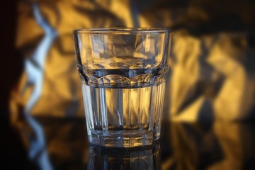 faceted glass half filled with water, gold background