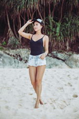 beautiful slim girl in cap posing at sandy beach