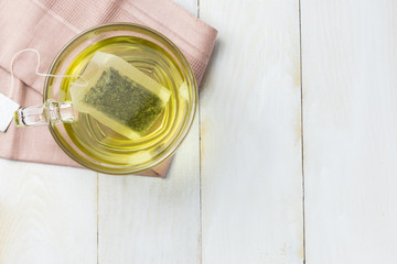 Hot green tea in glass placed on white wooden floor.