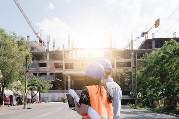 Architects And Engineer at a construction site looking at blueprints and pointing