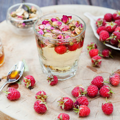 Herbal tea with rose buds and fresh raspberry.