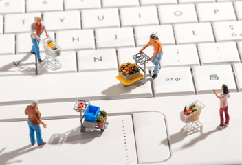 Miniature people with shopping carts on a keyboard