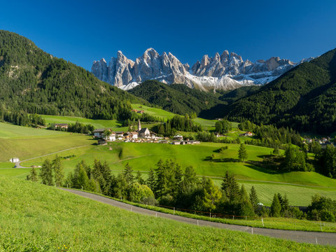 Val di Funes valley, Santa Maddalena touristic village, Dolomites, Italy, Europe. September, 2017. Green grass and blue sky.