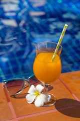 Orange juice sunglasses on swimming pool border