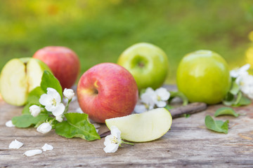 green red apples with flowers on wooden background
