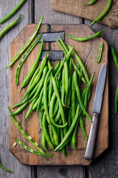 Green beans on wooden cutting board. Top view