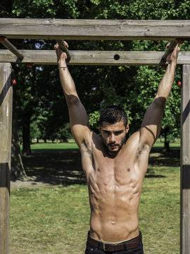 Attractive man exercising and working out in outdoor gym in city park