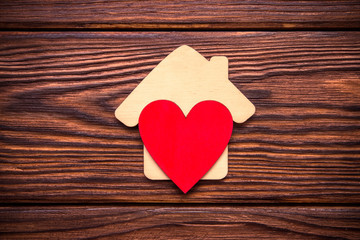 Fototapeta premium The symbol of the house with heart on wooden background 