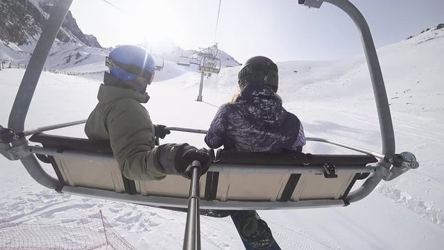 Snowboarders man and woman at ski lift chair ski resort