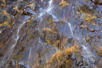 Reflets de ciel bleu à flanc de montagne entre roches et herbes, Pyrénées, France