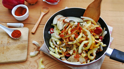Cooking lecho with sausage, bell peppers and onions, seaoned with red paprika and black peper in...