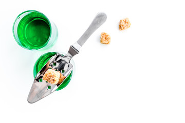 Traditions of drinking absinthe. Special spoon and sugar cubes near shots on white background top view copy space