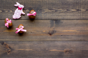 Easter composition. Easter sweet gift. Chocolate eggs near cookies in shape of Easter bunny on dark wooden background top view space for text