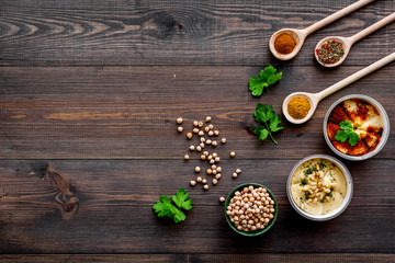 Cook chickpeas. Make hummus. Bowls with grains and ready meal near spices on dark wooden background top view copy space