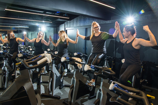 Happy sporty women holding hands support team unity in gym.