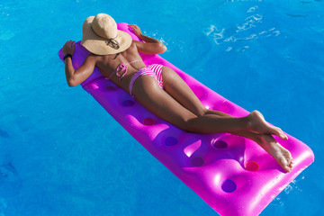 woman in straw hat gets suntan on an air mattress