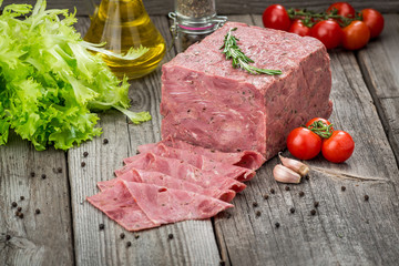 Cut sausage from ham on a wooden background