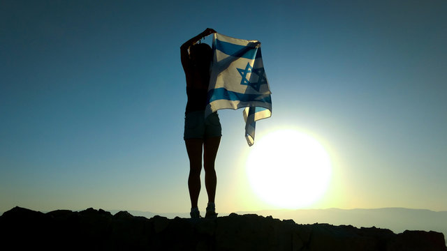 Jewish Young Woman Stands With Her Back On The Mountain And Holds The Flag Of Israel