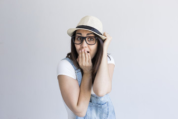 portrait of a young beautiful woman with modern glasses and hat. White background. Millennial. Hipster and lifestyle.Making a surprise gesture.