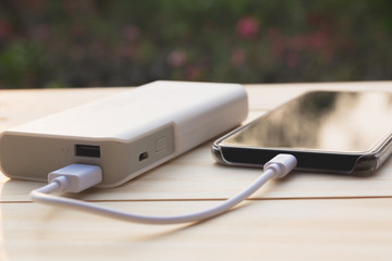 Mobile smart phones charging with power bank on desk.