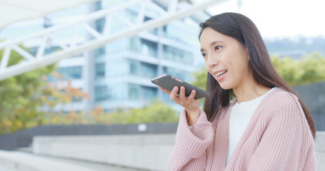 Woman sending audio message on cellphone at outdoor