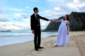 wedding dance of young bride and groom at the beach, mountain and blue sky with clouds and the back