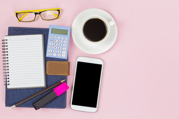 Notebook cover blue denim with empty label mobile calculator and black coffee white cup yellow glasses on pink background pastel style with copyspace flatlay.