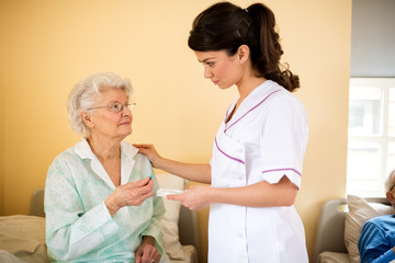 Careful young nurse brings medicine to her patient