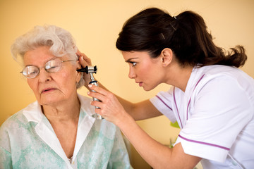 Doctor examining ear to senior woman