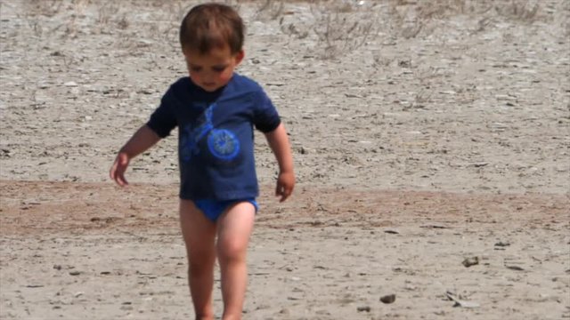 Slow motion of a toddler walking at the beach in underwear