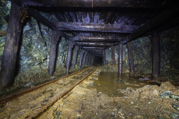 Underground abandoned gold ore mine shaft tunnel gallery with wooden timbering