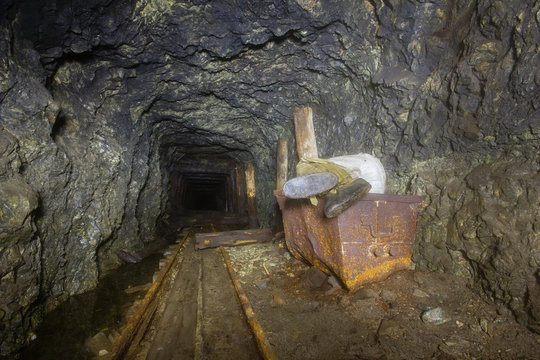 Underground abandoned ore mine shaft tunnel gallery with ore cart and sleeping miner